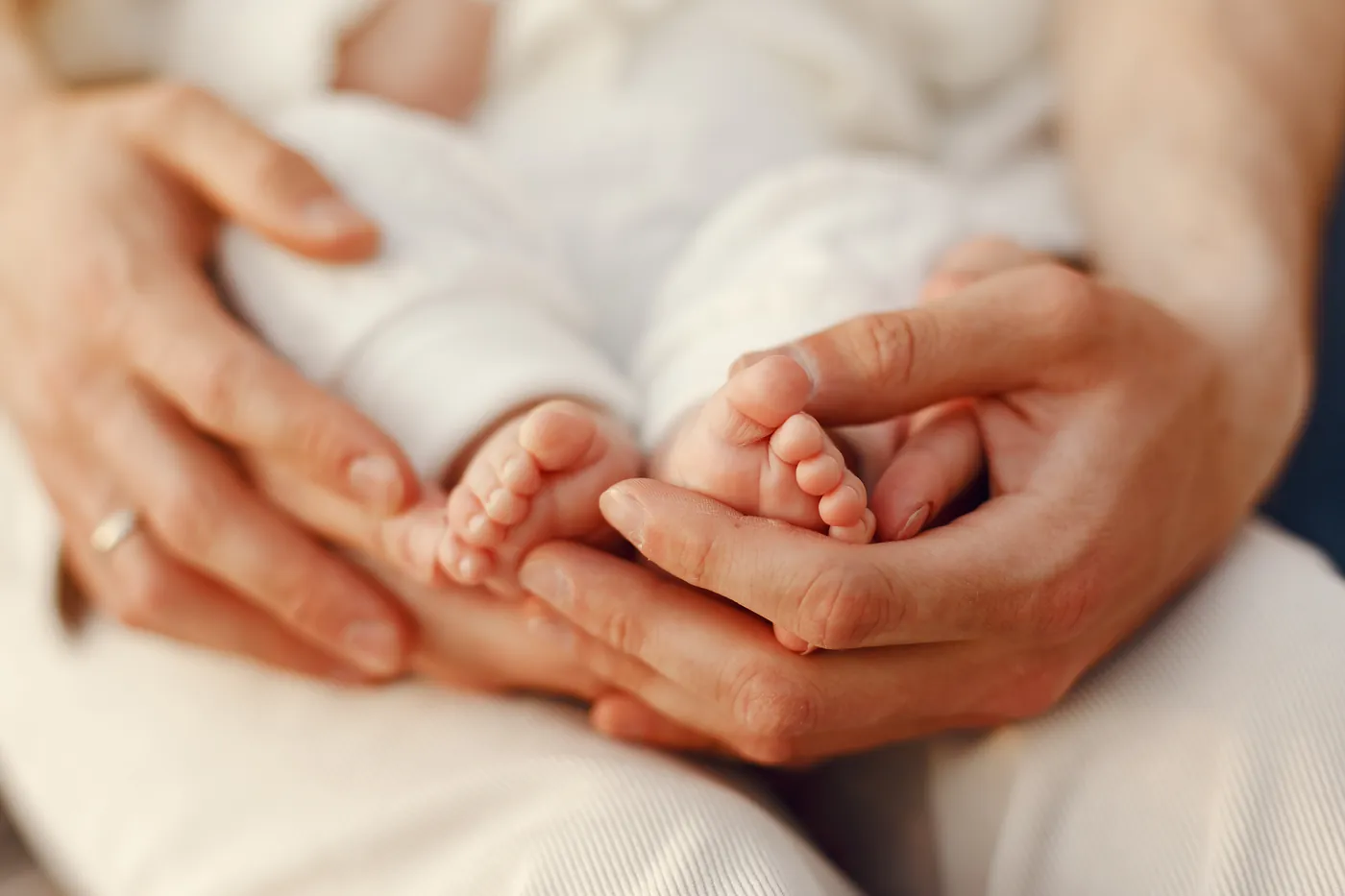 Mãos de adultos segurando os pés de um bebê